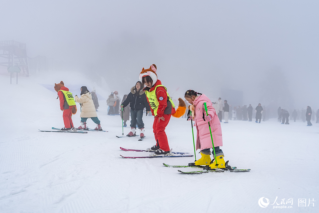 2026年1月10日，贵州六盘水野玉海国家级旅游度假区内的玉舍雪山滑雪场内，滑雪教练在教小朋友滑雪。作为西南地区规模领先的冰雪度假目的地，六盘水以冰雪旅游为引擎，推动“运动+度假+文化+研学”融合发展，使冬季旅游从“小众体验”走向“大众市场”。人民网记者 涂敏摄