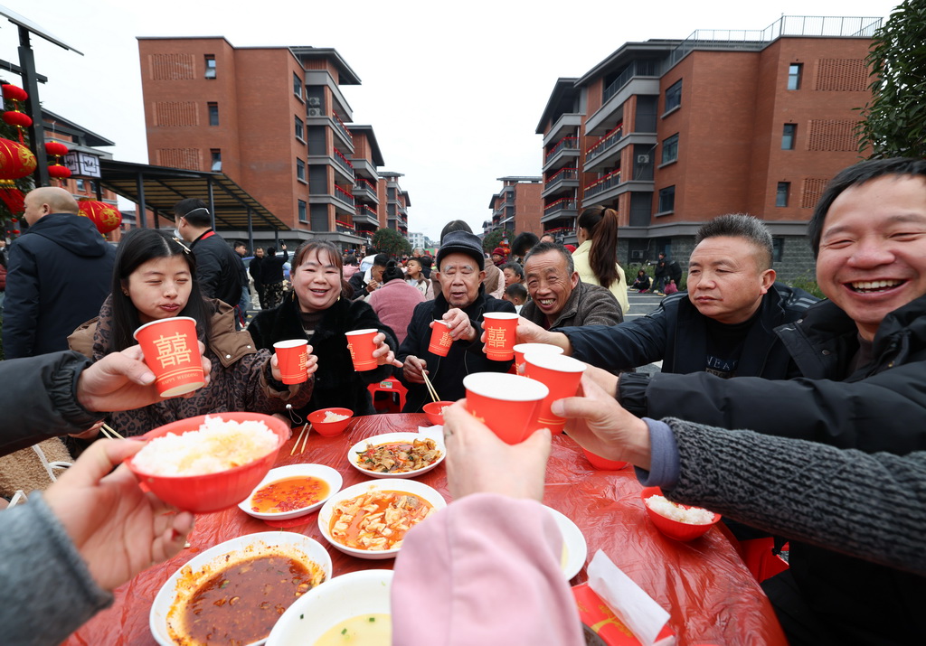 1月31日，在四川省宜賓市筠連縣沐愛鎮金坪村搬遷安置區，受災群眾在百家宴上舉杯相互祝福。