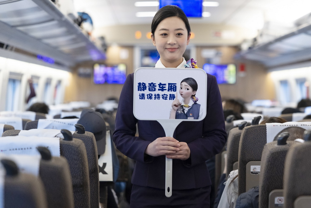 2月1日,铁路上海客运段乘务员在G12次列车车厢内手举静音车厢提示牌。新华社记者 王翔 摄