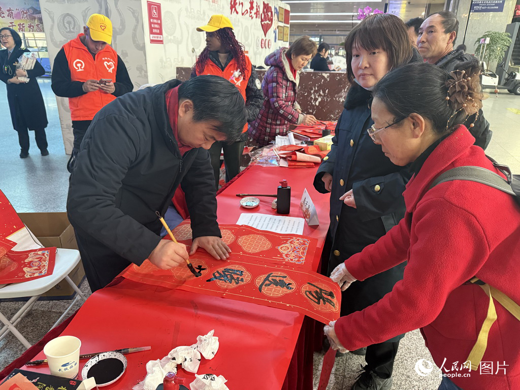 2月2日春運第一天，在武昌火車站，書法愛好者為春運回家旅客寫春聯。人民網記者 張沛攝