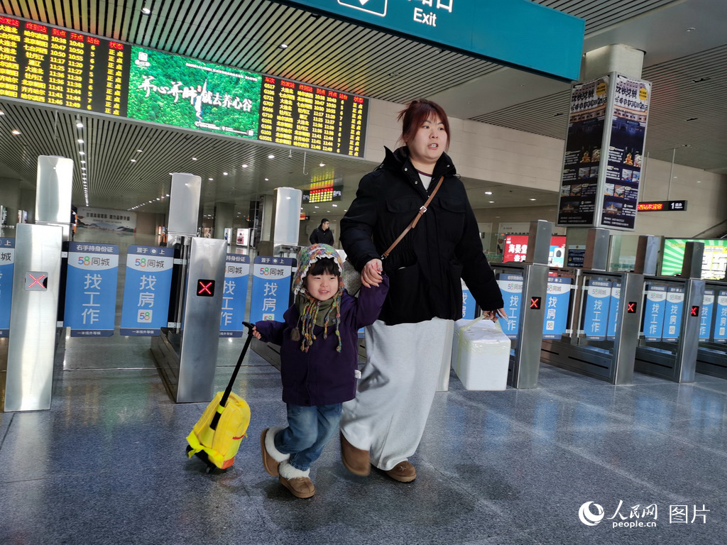 2月2日，在長春西站，現住大連的於女士一家三口回長春娘家探親，孩子的笑容溫暖了站台。人民網記者 王帝元攝