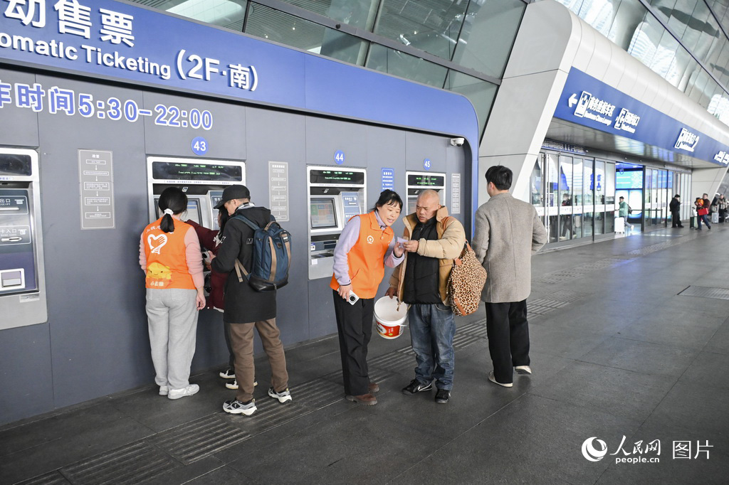 2月1日，杭州東站自動售票機前，志願者為旅客提供幫助。人民網記者 葉賓得攝