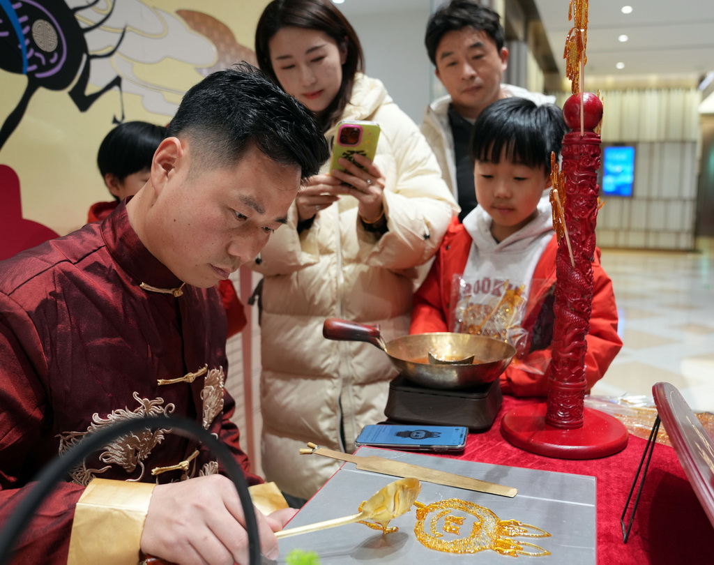 2月1日晚,在BFC外滩金融中心商场,手工艺人制作玩偶糖画。