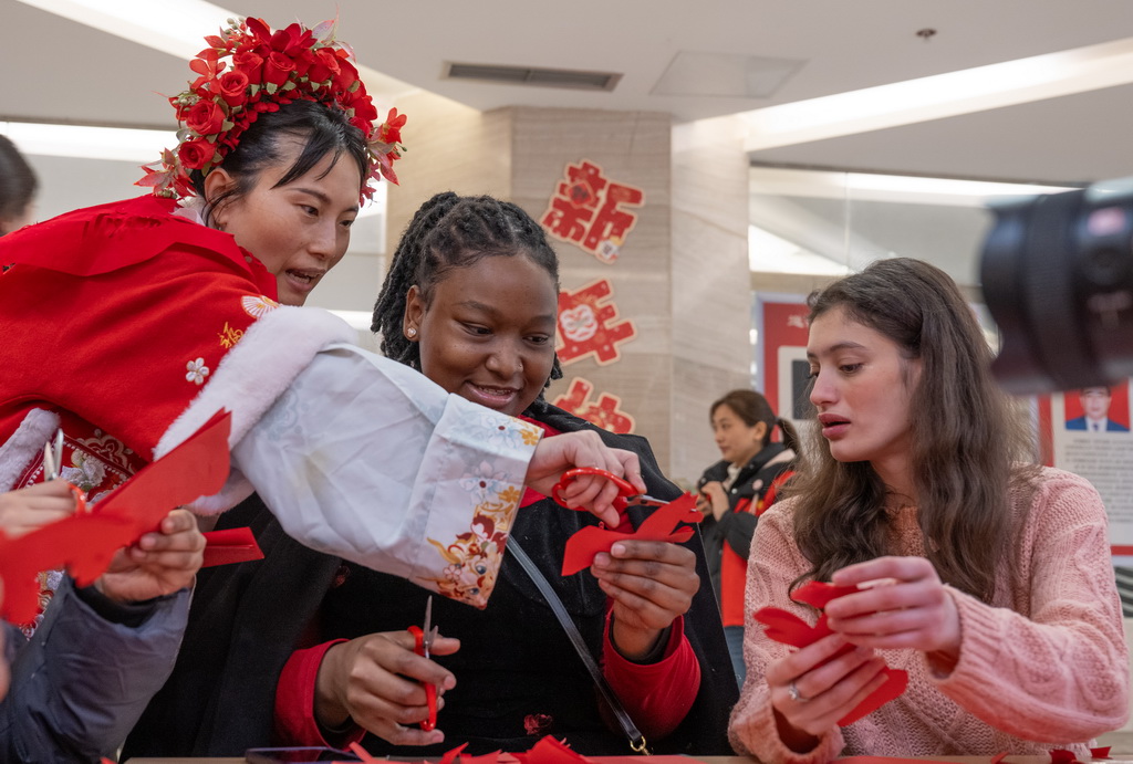 2月3日,在重慶市巴南區,留學生在老師的指導下體驗剪紙。