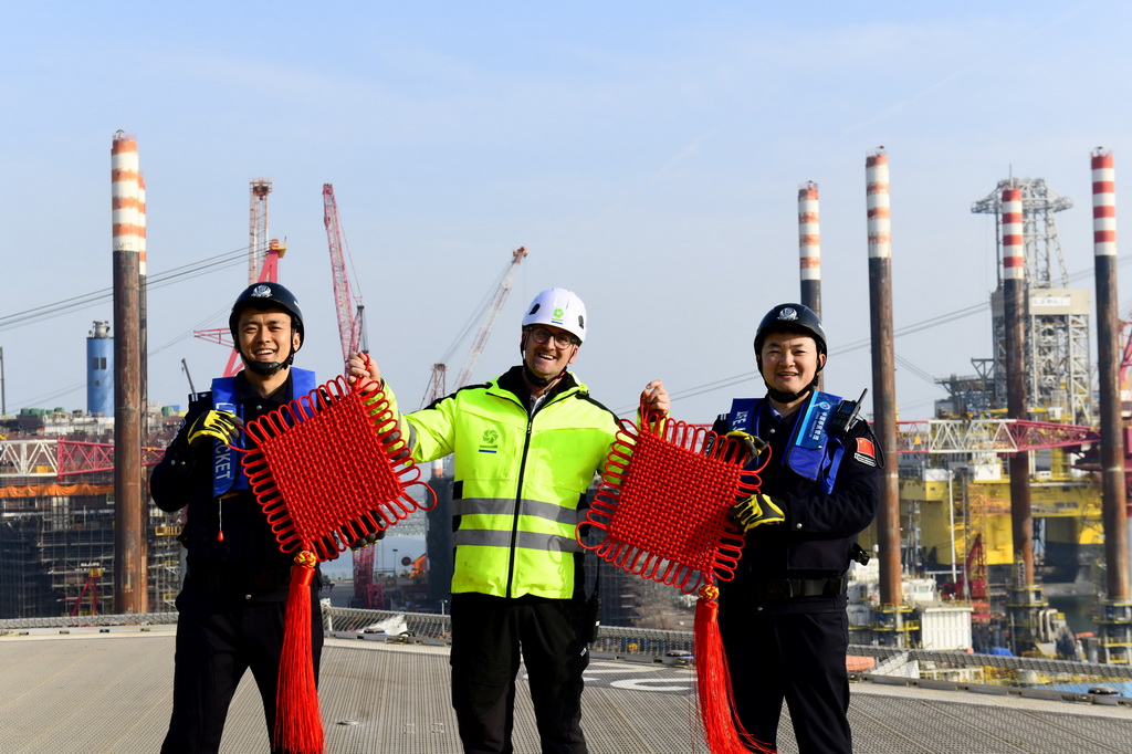 2月3日,在中集来福士山东烟台建造基地,山东出入境边防检查总站烟台边检站来福士警务室的民警赠送比利时风电安装船船长中国结,并合影留念。