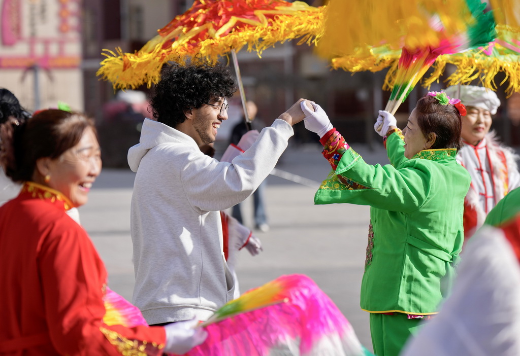 2月5日,北方民族大学国际教育学院的留学生在宁夏银川市西夏区芦花洲社区和当地居民一起扭秧歌。