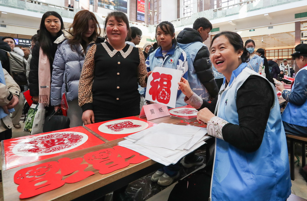 2月10日，文化志愿者在完成剪纸作品后与旅客合影。
