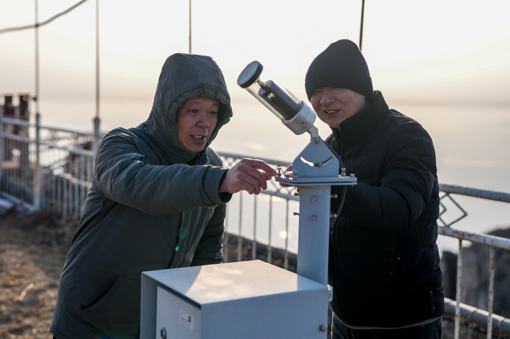 2月7日，副站长杨瑞峰（左）和观测员刘恒德在泰山气象站观测场内检查仪器设备。