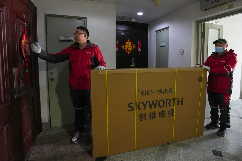 2月11日,在北京市朝阳区一个小区内,京东快递的快递员在配送消费者使用国家补贴购买的电视机。