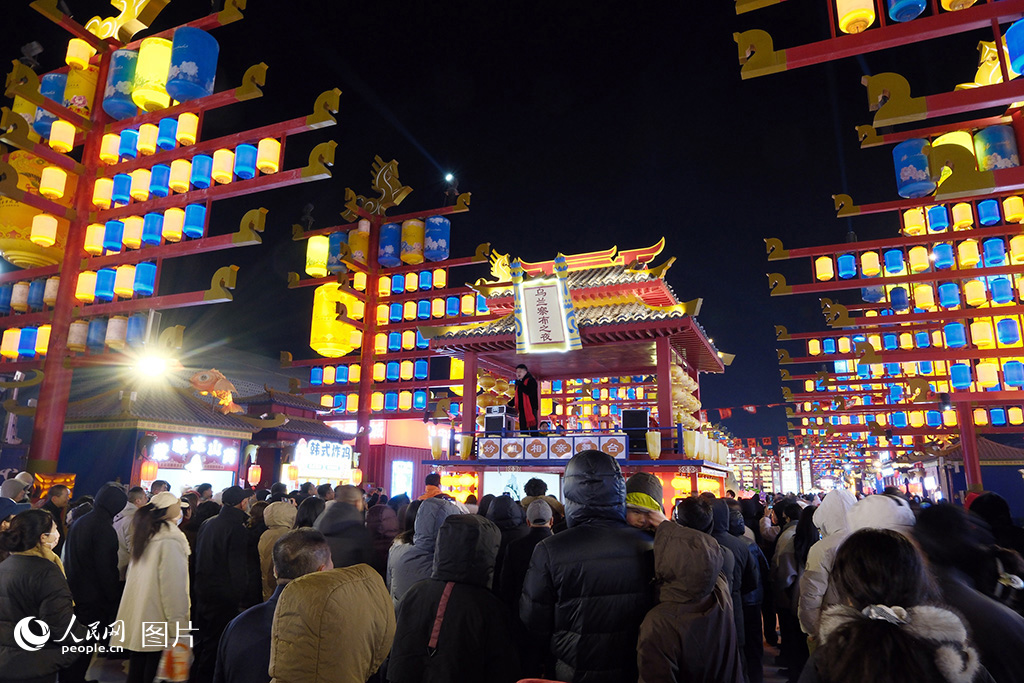 2026年2月17日晚，在内蒙古自治区乌兰察布市察哈尔右翼前旗，乌兰察布之夜街区灯火璀璨、热闹非凡，吸引全国各地游客打卡。图为游客们正在与街区工作人员互动。人民网记者 刘艺琳摄