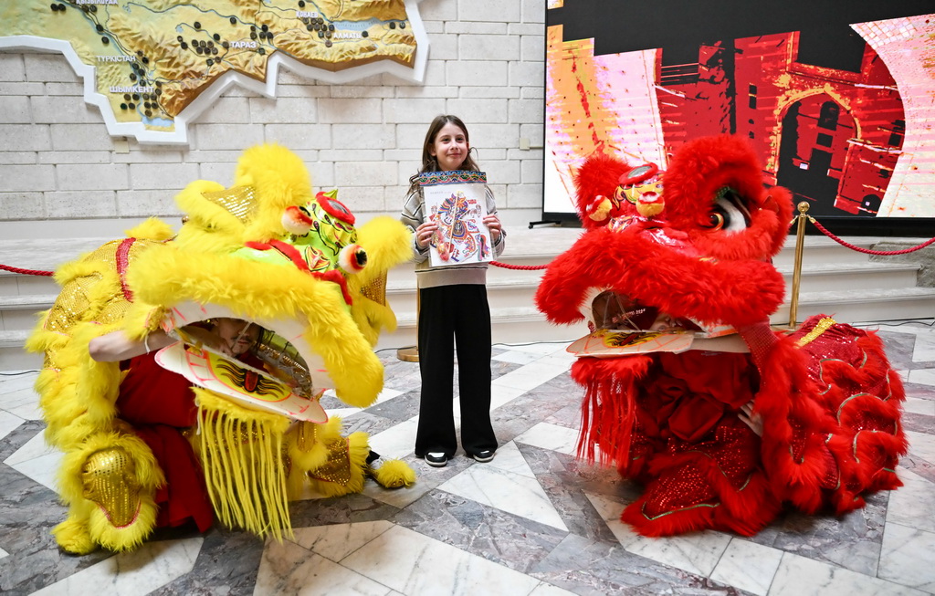 2月23日,在位于阿拉木图的哈萨克斯坦中央国家博物馆,一名女孩在开幕式后与舞狮合影。