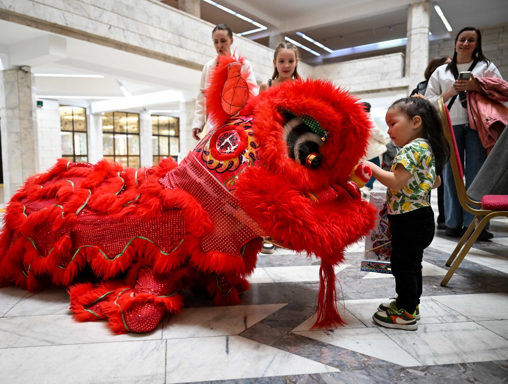 2月23日，在位於阿拉木圖的哈薩克斯坦中央國家博物館，一名女孩在開幕式后與舞獅互動。