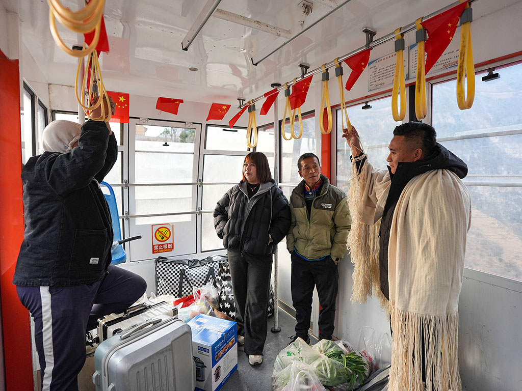 1月28日,鄭望春在古路村索道車廂內和外出務工返鄉的村民交流。