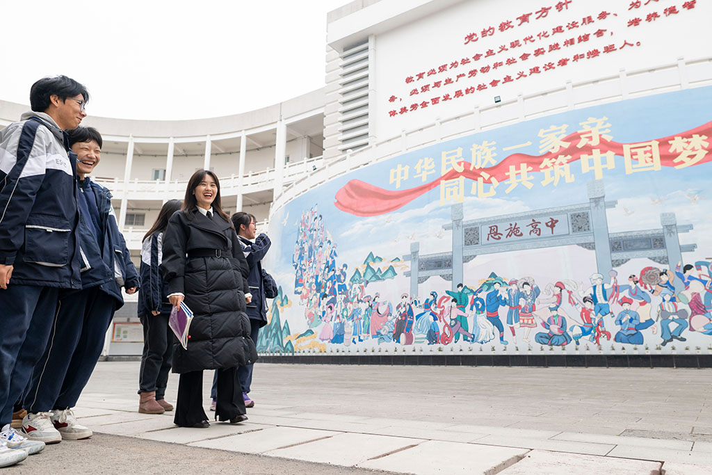 2月4日,在恩施土家族苗族自治州高級中學,張瓊麗(右二)與學生從“中華民族一家親 同心共筑中國夢”文化牆前走過。
