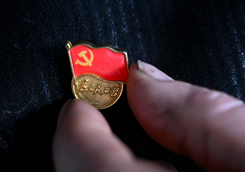 2月9日，在伊犁哈萨克自治州新源县，木沙江·海拉特在家中佩戴党徽准备出门。他要去克热格塔斯村党群服务中心听取群众的意见建议。新华社记者 王菲 摄