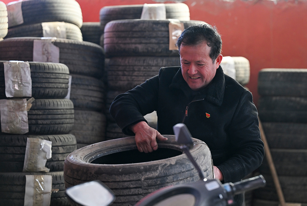 2月9日，在伊犁哈萨克自治州新源县克热格塔斯村，木沙江·海拉特在自己家中的工坊搬运轮胎。每年冬天，木沙江免费为周边村民提供存胎服务。新华社记者 王菲 摄