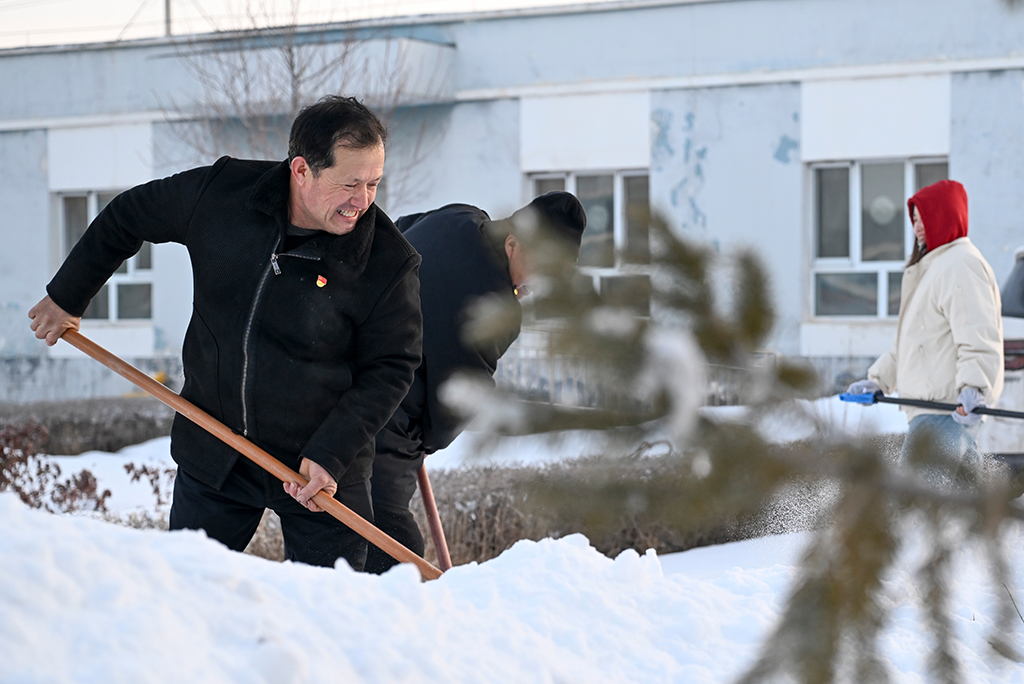  2月9日，在伊犁哈萨克自治州新源县，木沙江·海拉特（前）在克热格塔斯村党群服务中心和当地干部一起清理积雪。新华社记者 王菲 摄
