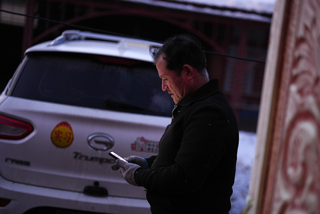  2月9日，在伊犁哈萨克自治州新源县，木沙江·海拉特在自家的院子里查看乡亲发来的电焊需求。新华社记者 辛悦卫 摄