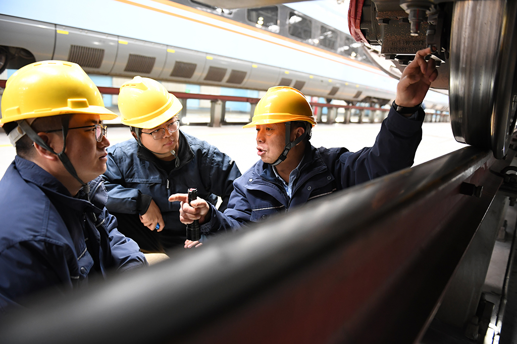   1月14日，在位於中國鐵路西安局集團有限公司西安動車段的動車組檢修庫，董宏濤（右）和青年職工一起檢修動車組列車。