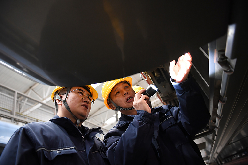  1月14日，在位于中国铁路西安局集团有限公司西安动车段的动车组检修库，董宏涛（右）和青年职工一起检修动车组列车。