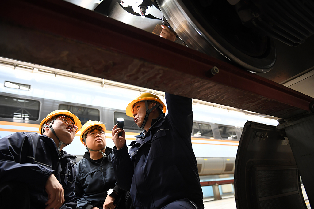  1月14日，在位於中國鐵路西安局集團有限公司西安動車段的動車組檢修庫，董宏濤（右）和青年職工一起檢修動車組列車。