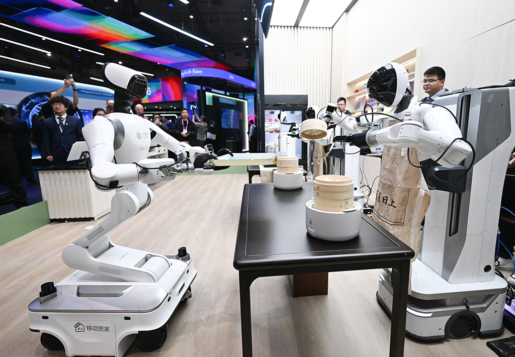 3月2日,在西班牙巴塞罗那,人们在中国移动展台参观厨房机器人。