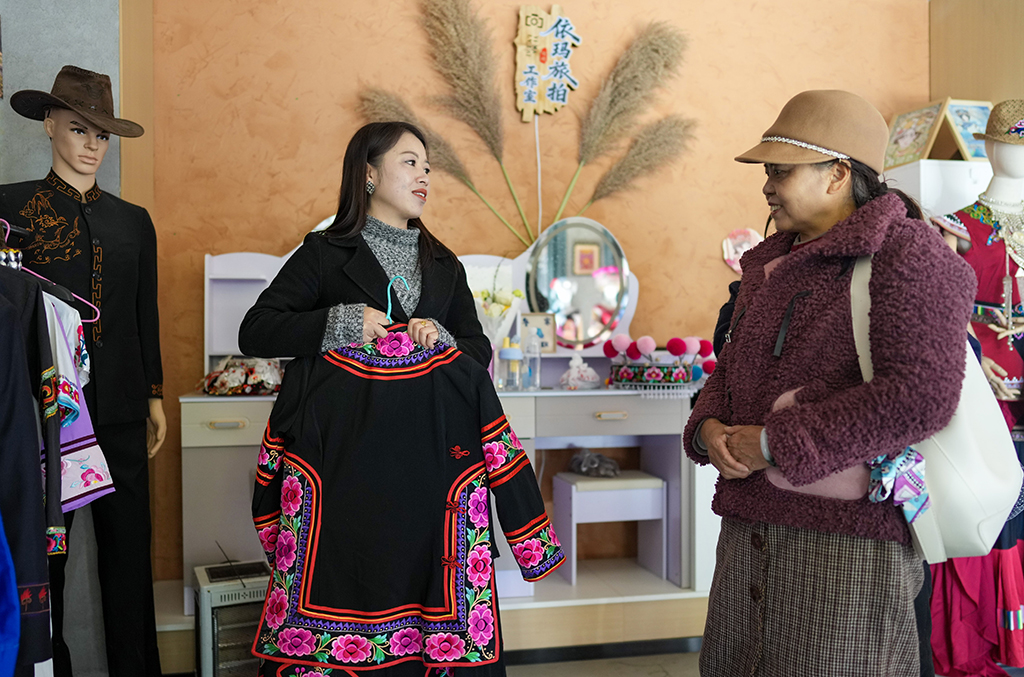 2月10日，金瑞瑞在自己的工作室内为顾客介绍彝绣服饰。