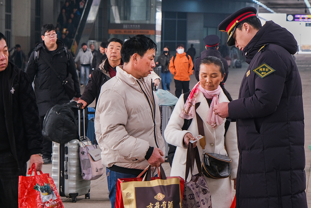 3月2日，T253次列车长在天津站站台解答旅客问询。