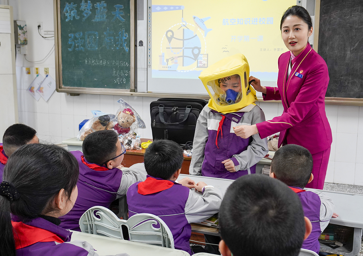 3月5日,在重慶市九龍坡區謝家灣朵力小學校的課堂上,來自重慶航空的空乘人員和學生一起演示如何正確使用客機上的應急處置裝備。