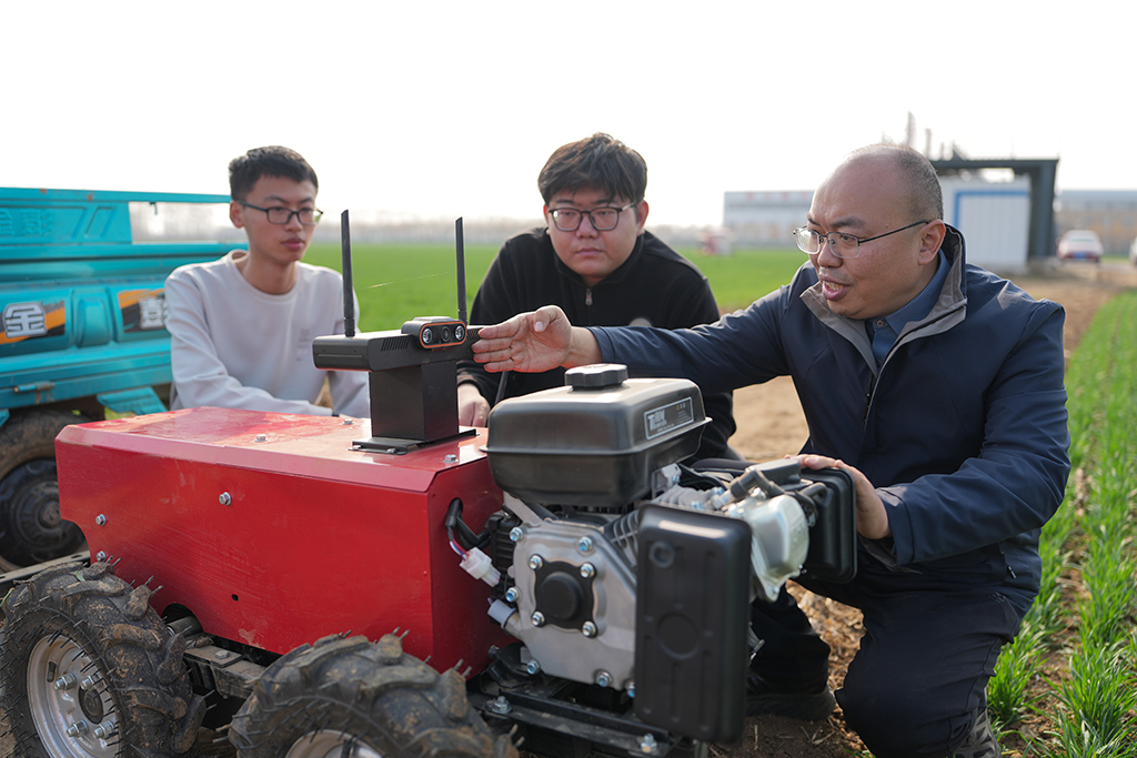 3月9日,山東農業大學副教授陳國慶(右)和團隊成員在調試農田作業通用機器人。