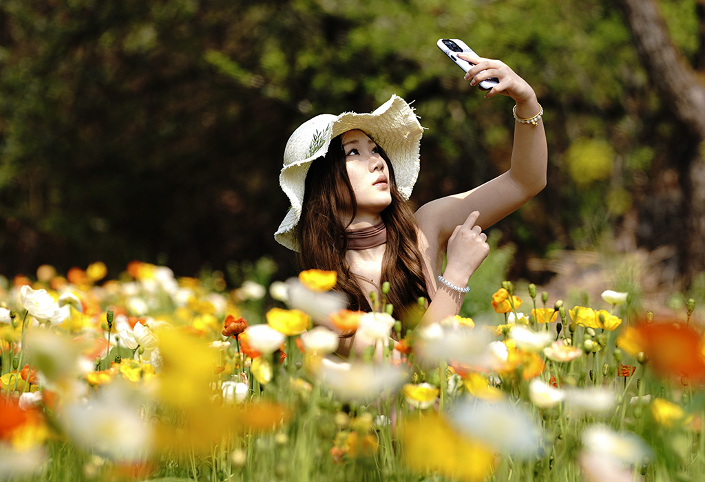 3月10日，一名游客在昆明名花谷的虞美人花叢旁拍照。