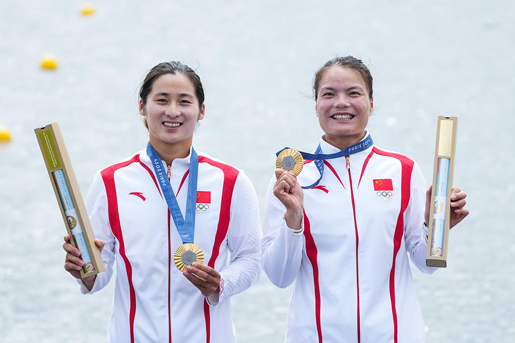 2024年8月9日，中國組合徐詩曉（右）/孫夢雅在巴黎奧運會皮劃艇靜水女子雙人劃艇500米決賽中奪得冠軍后，在頒獎儀式上展示金牌。新華社記者 杜宇 攝