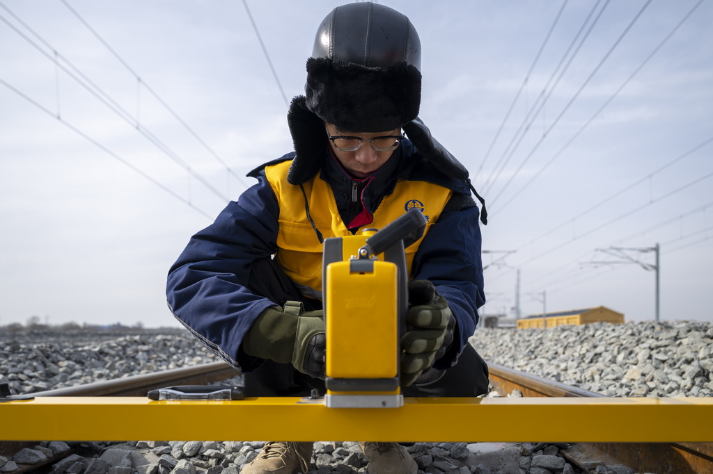 3月13日,工人在哈伊高鐵綏化南站施工現場進行測量作業。