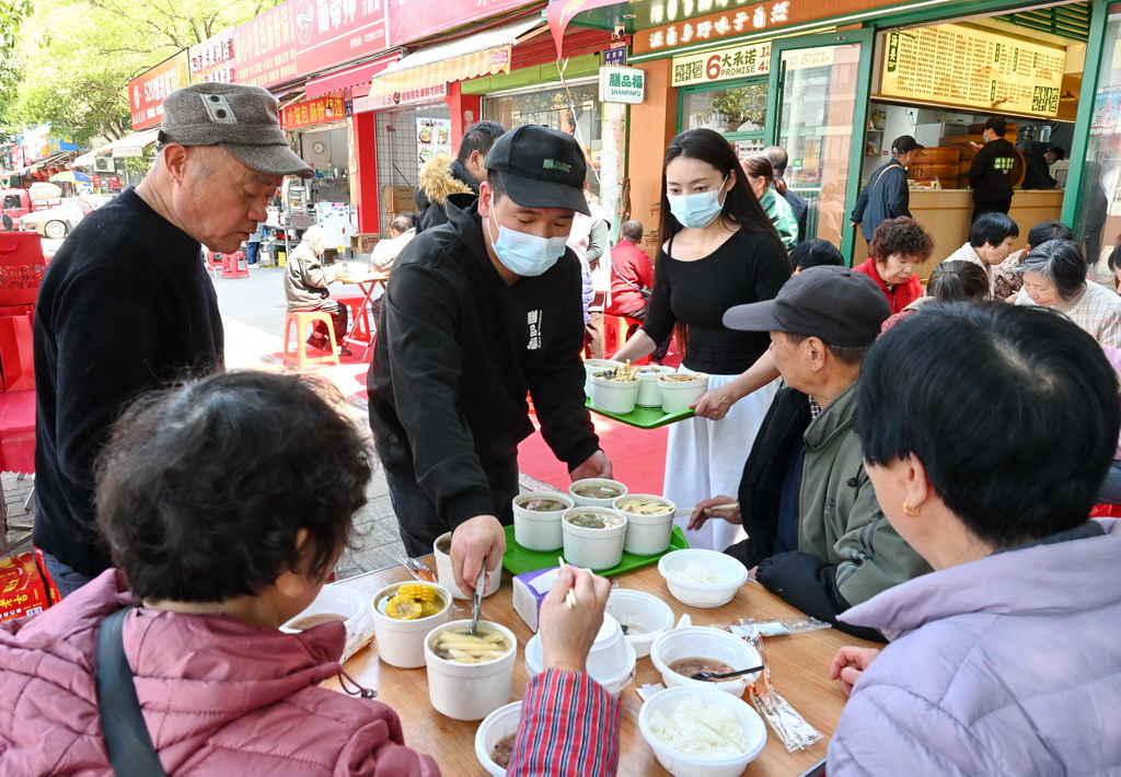 3月17日，在福州市仓山区后巷路，一位餐饮店主（左三）向老人赠送“拗九粥”和炖品。
