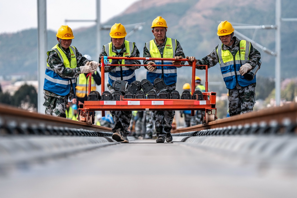 3月18日，工人在渝昆高铁施工现场进行铺轨作业。