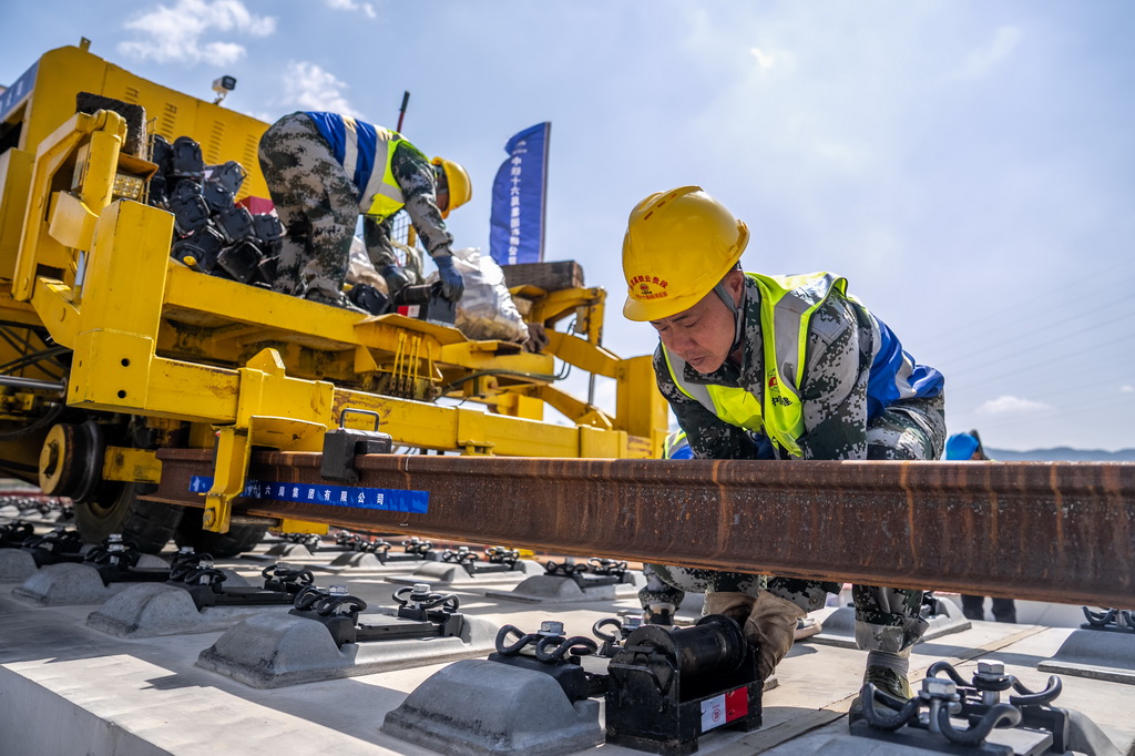 3月18日，工人在渝昆高铁施工现场进行铺轨作业。
