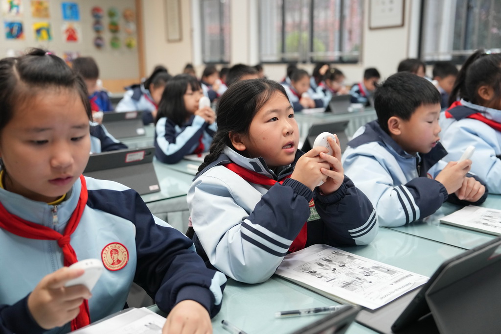 3月17日,在湖南湘江新区雷锋小学,学生在英语课上手持语音答题器回答老师问题。他们的答题录音将实时同步至教学终端,教师能结合人工智能的学情分析功能,精准掌握每位学生的发音情况。