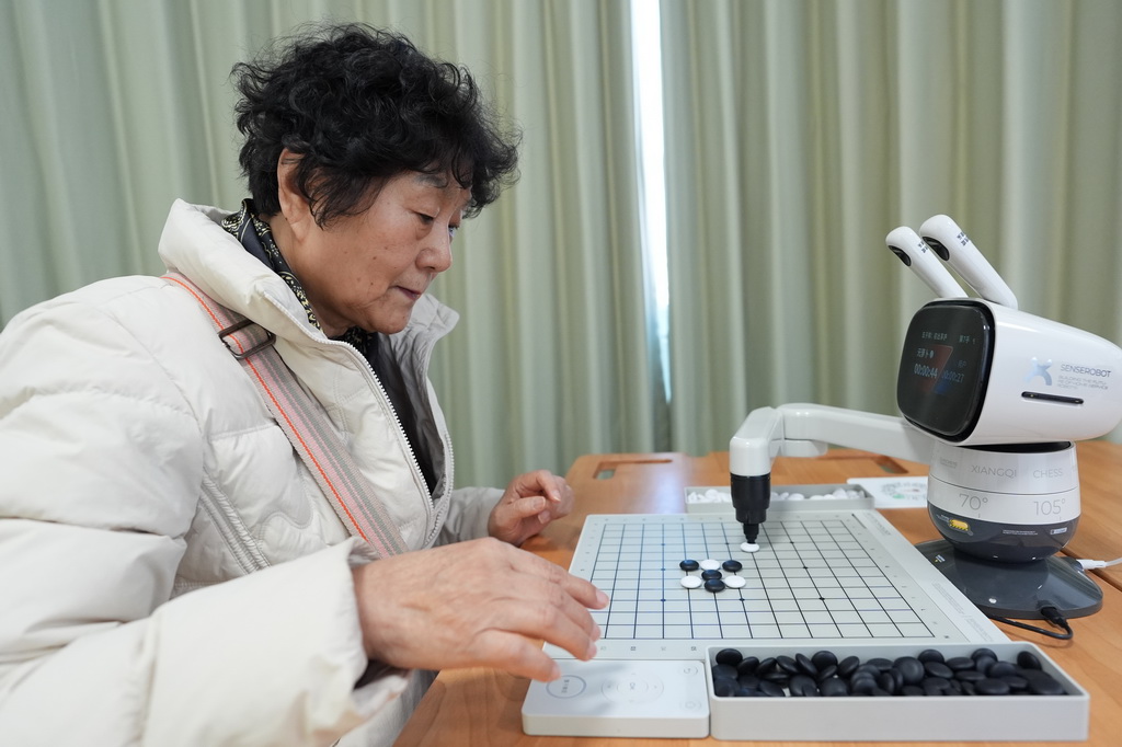 在智慧康养机器人养老驿站内,一名社区居民与一款机器人下五子棋(3月18日摄)。