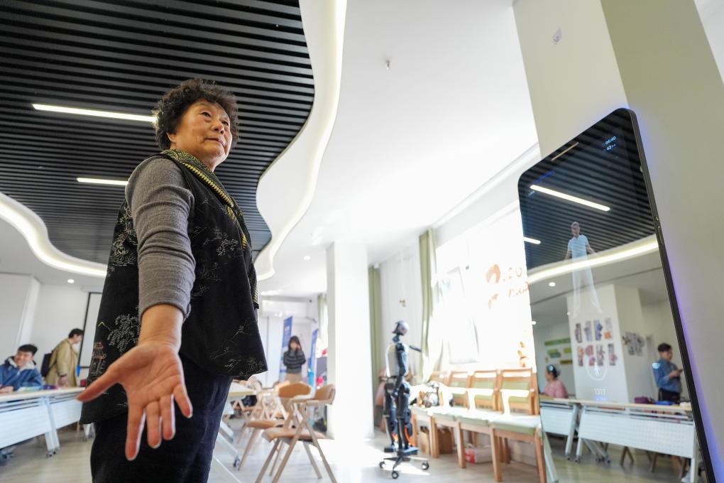 在智慧康养机器人养老驿站内,一名社区居民跟随一款智能设备练习八段锦(3月18日摄)。