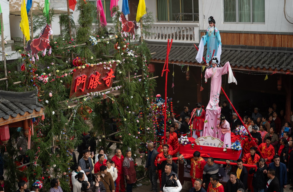 3月20日,四川省兴文县九丝城镇建武村,演员在巡游活动中表演木台铁桩戏《山伯访友》。