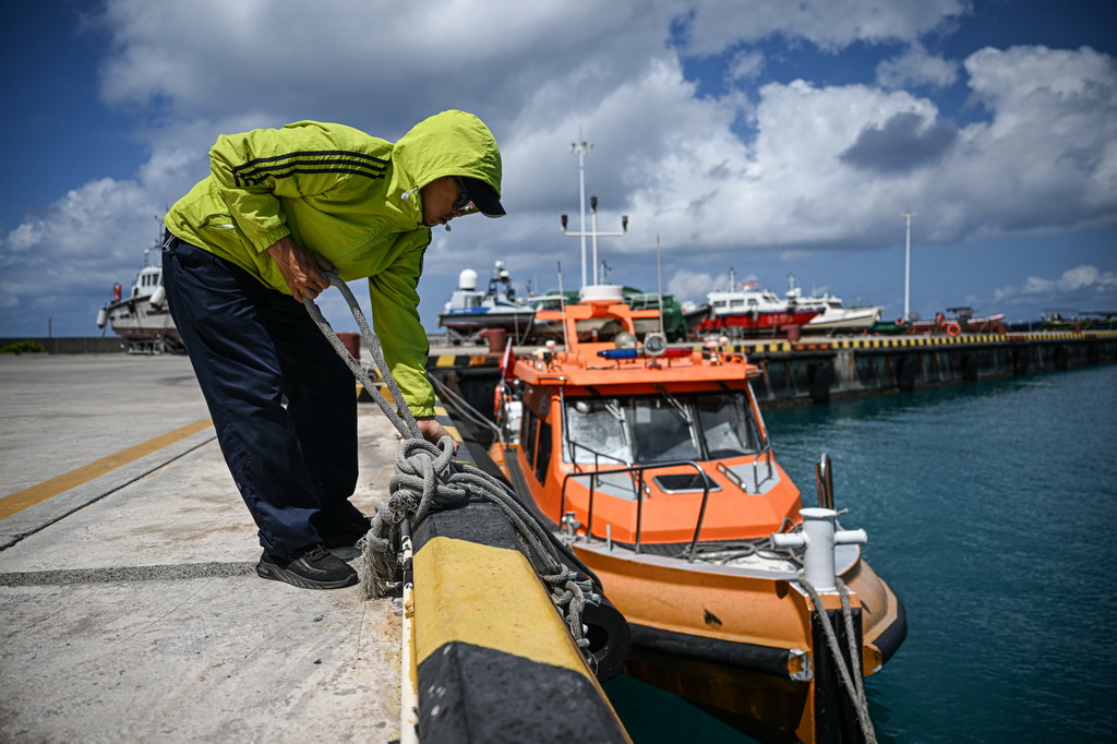 3月19日，在海上交通保障船抵達海南三沙永興島碼頭后，工作人員整理纜繩准備固定船隻。新華社記者 蒲曉旭 攝