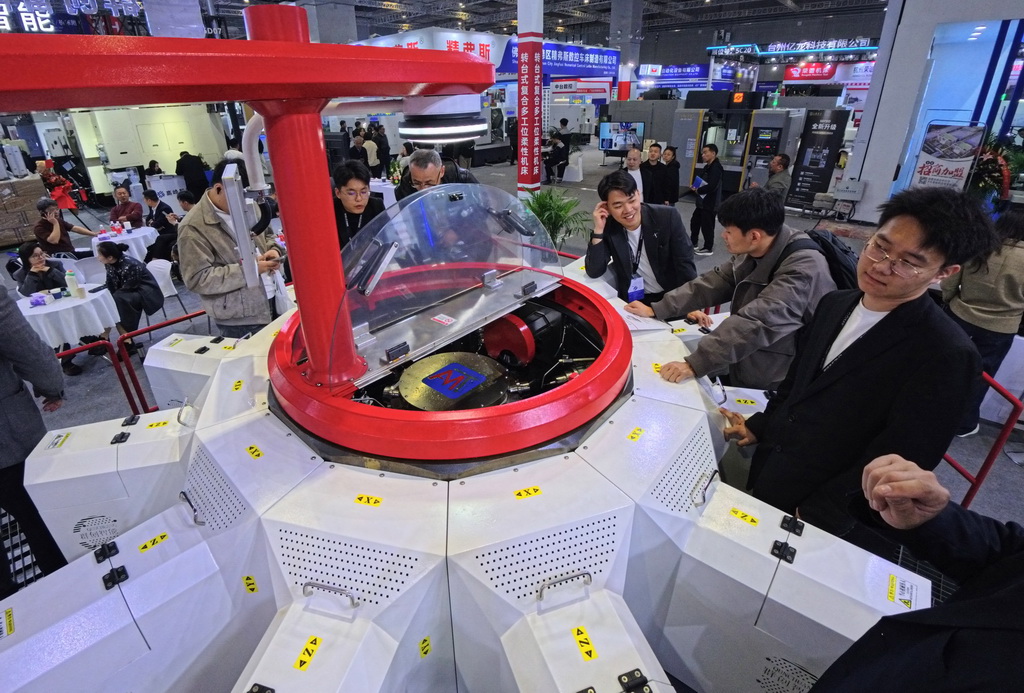 3月23日，参观者在一款转台式多工位柔性复合机床展品旁观看交流。