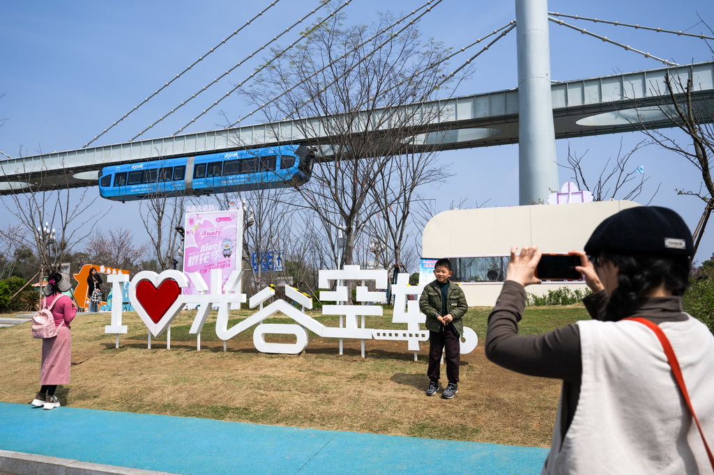 3月21日,游客在一列空轨列车驶过时拍照留念。