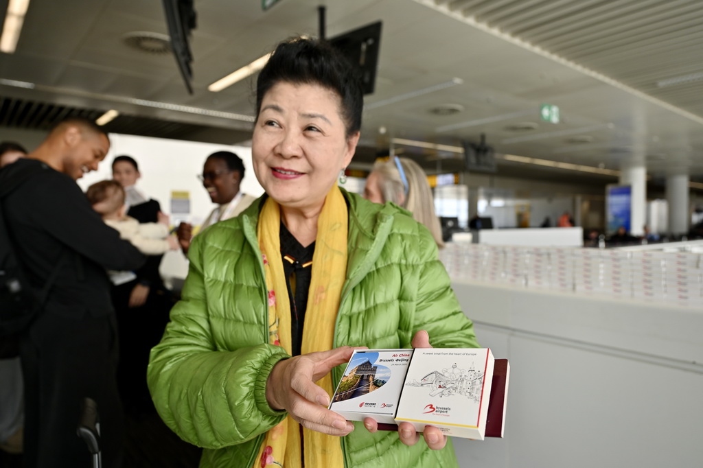 3月24日，在比利时布鲁塞尔国际机场，搭乘首航航班的乘客展示首航纪念品。