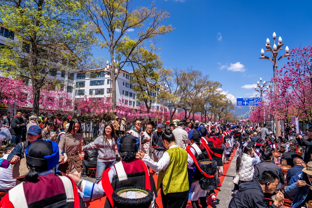3月26日,人們在麗江市雪山路長街宴活動現場打跳。