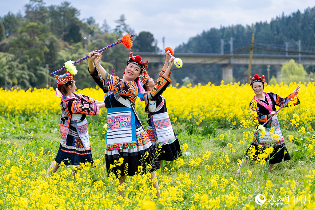 2026年3月13日，贵州贵阳乌当区新堡布依族乡，身着苗族传统服饰的姑娘在油菜花田里跳花棍舞。人民网记者 涂敏摄