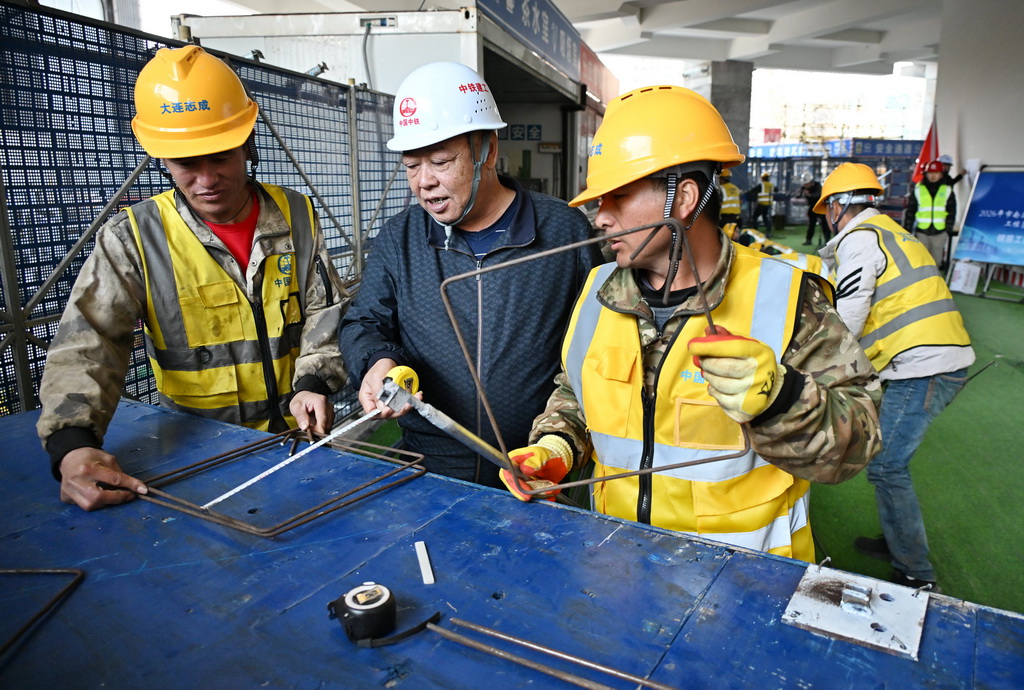 4月8日，在青島市南京路1號項目比賽現場，一名評委（左二）在鋼筋工團體賽中測量鋼筋。