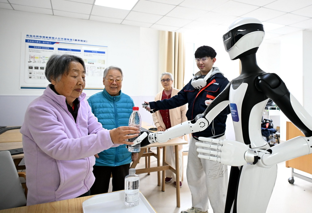 4月9日，在青島市康養領域具身機器人暨智能康復類產品訓練驗証中心，機器人在訓練師指導下與老人互動。