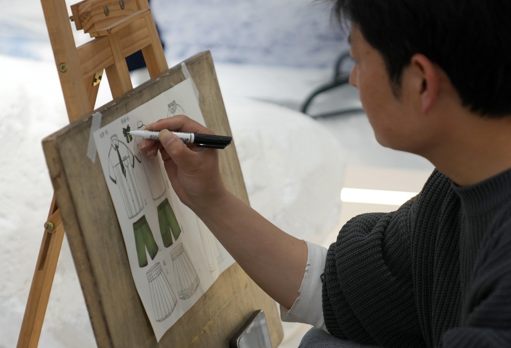 4月13日，在织里镇一家童装企业内，一名设计师在打磨校服产品的设计稿。