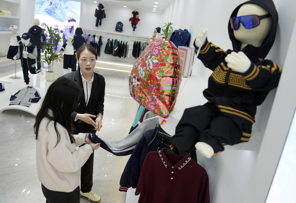 4月13日，织里镇一家童装企业的员工在产品陈列室内向客户介绍童装产品。
